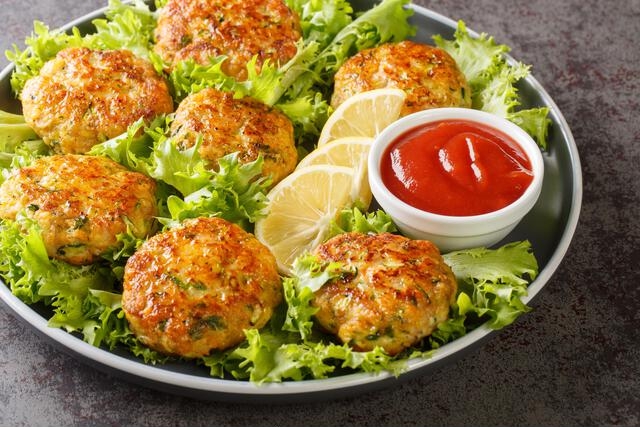 juicy delicious fried chicken cutlets with cheese, carrots, zucchini and herbs close-up in a plate on the table